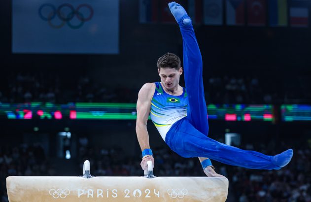 Ginasta brasileiro estende perna no ar ao realizar movimento no cavalo com alças, Paris 2024.