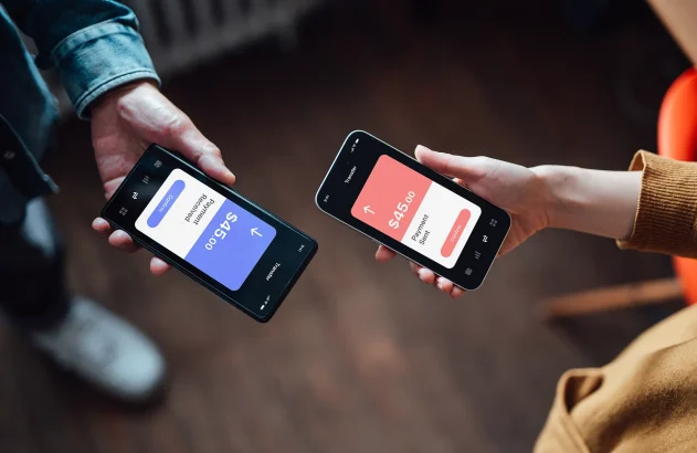 Close de duas pessoas diferentes segurando um smartphone em cuja tela se vê uma transação bancária; pix ; transferência; banco