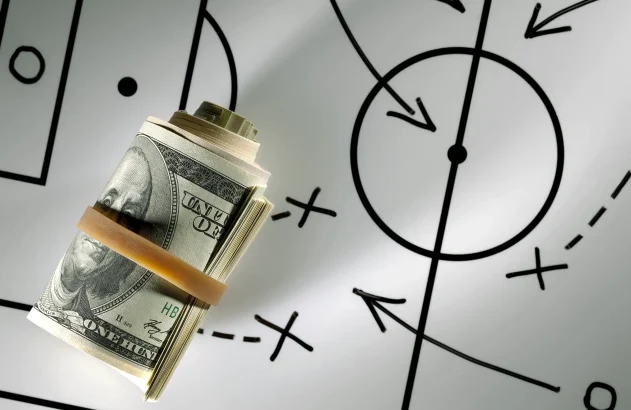 Rolo de dólares em um quadro negro com planejamento estratégico de futebol