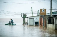 Dois homens andam de barco na Praia do Lami durante as chuvas em uma área afetada pelas enchentes em 10 de maio de 2024 em Porto Alegre, Brasil. Foto: Jefferson Bernardes/Getty Images