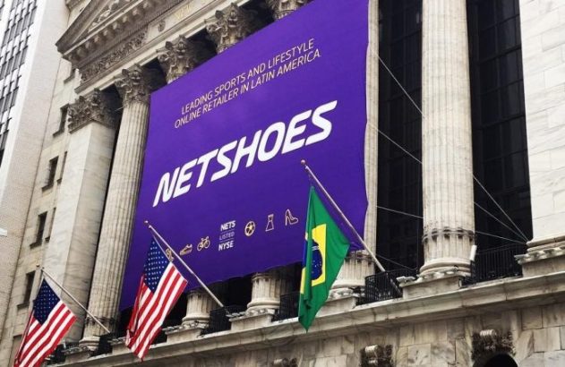 Banner roxo da Netshoes no prédio da NYSE, celebrando a listagem, com bandeiras dos EUA e Brasil.