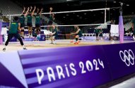 Time de vôlei do Brasil treina em quadra para Paris 2024, com jogadores saltando para ataque e bloqueio.