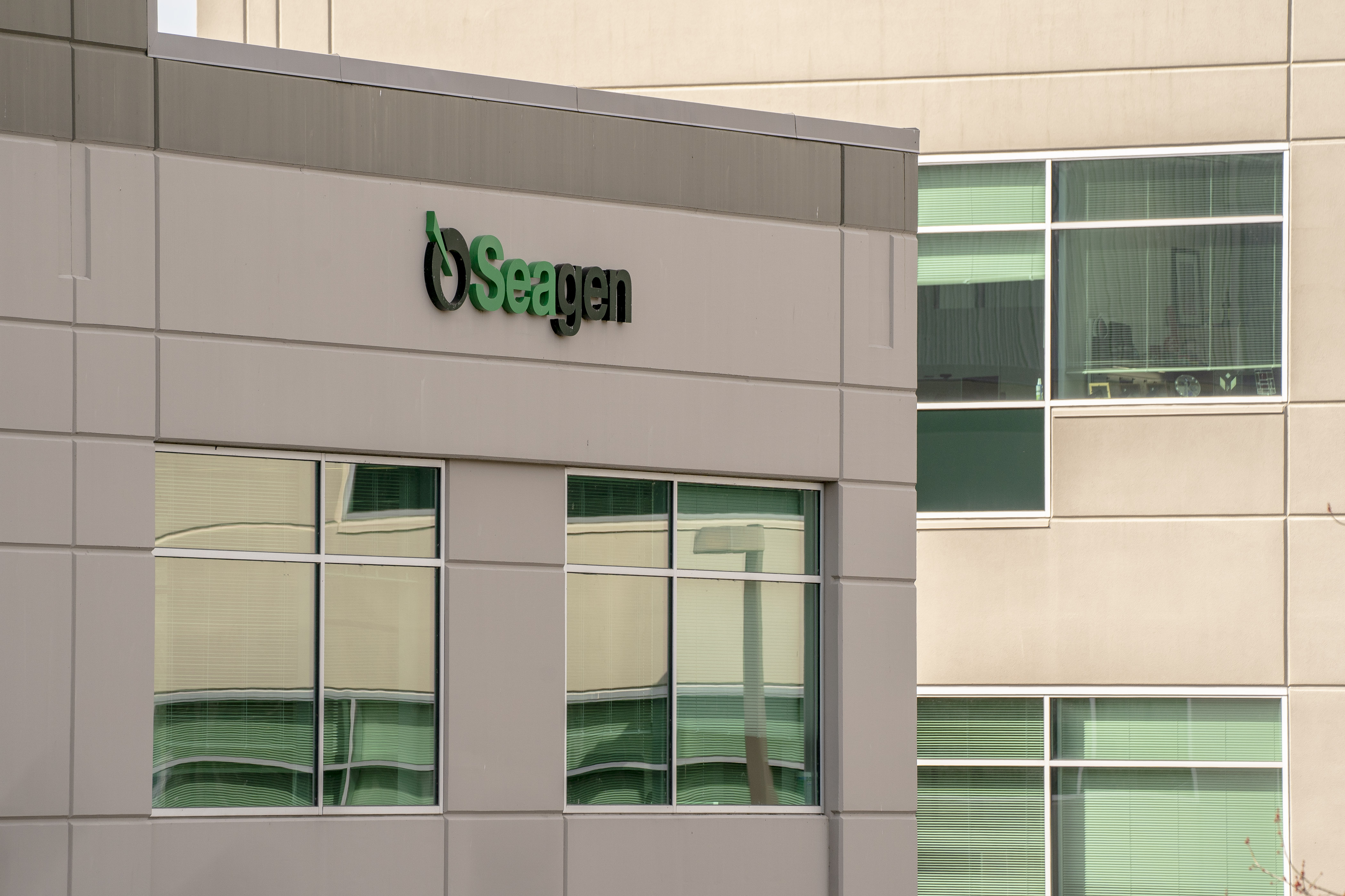 Logotipo verde e preto "Seagen" na fachada de um edifício com janelas.