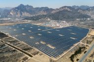 Usina solar em campo aberto com painéis fotovoltaicos e montanhas ao fundo.