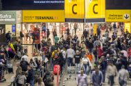 Aeroporto: multidão em movimento, balcões de check-in e sinalização para embarques.