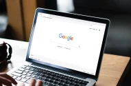 Um homem digitando no mecanismo de busca Google em um laptop