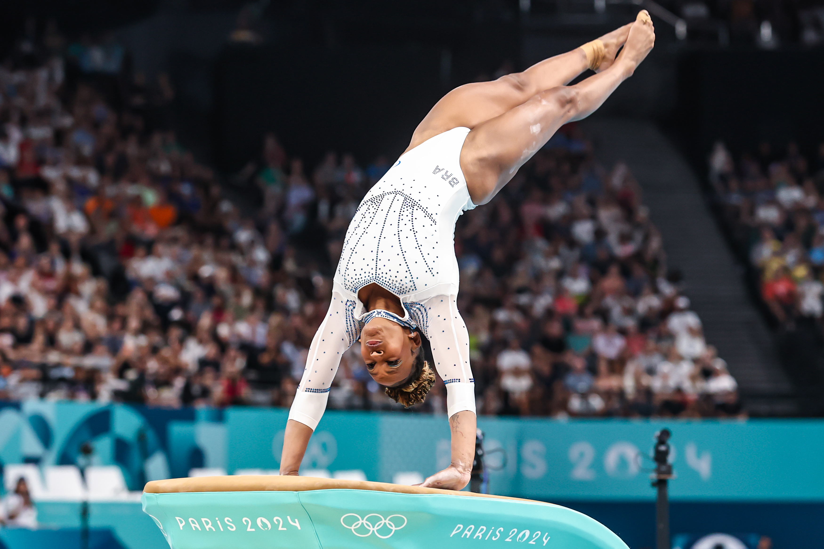 Ginasta em parada de mãos na mesa de salto Paris 2024.