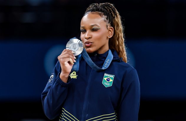 Atleta brasileira de tranças beija medalha de prata em uniforme.