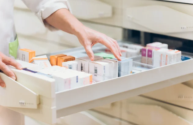 Mão de farmacêutico tirando medicamento da gaveta