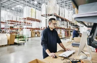 Trabalhador de depósito verificando pedidos em uma estação de trabalho; deposito; e-commerce