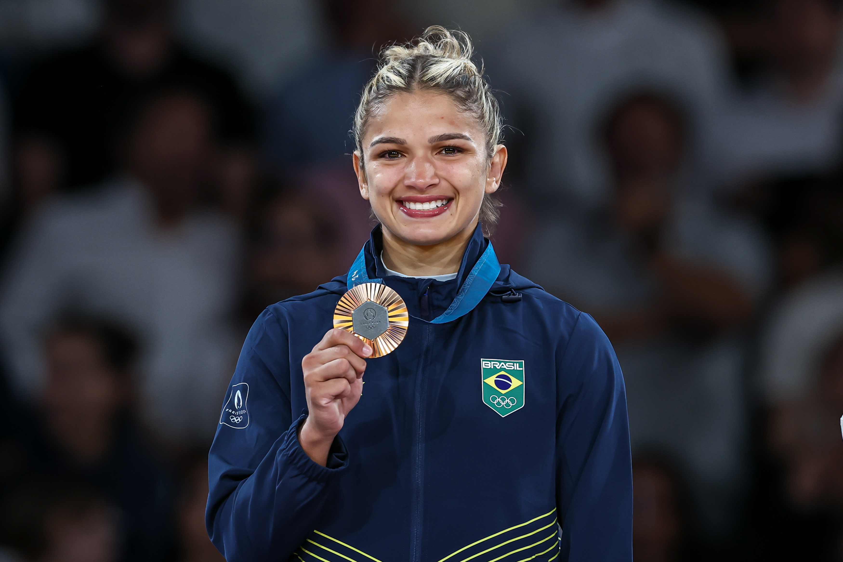 Atleta brasileira sorrindo, exibindo medalha de bronze dos Jogos Olímpicos.