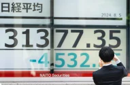 Um pedestre tira uma fotografia de monitores exibindo o número do Nikkei 225 Stock Average do lado de fora de uma empresa de valores mobiliários em 05 de agosto de 2024 em Tóquio, Japão. O índice Nikkei 225 em Tóquio sofreu um declínio significativo, despencando quase 7% em 4 de agosto de 2024, quando caiu para cerca de 33.488,08 pontos logo após a abertura do mercado. (Foto: Tomohiro Ohsumi/Getty Images)