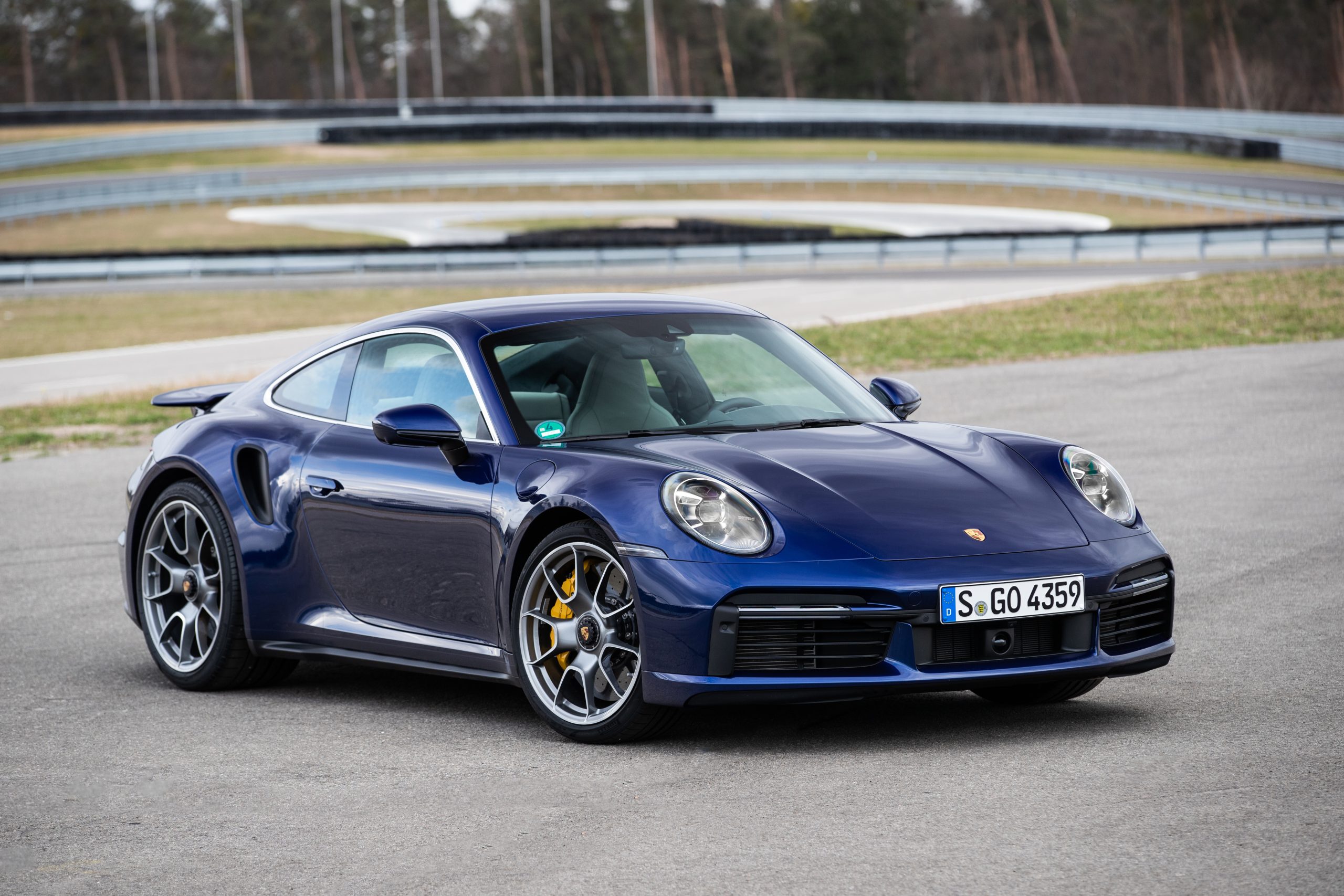 Porsche 911 azul em pista de corrida. Visão frontal-lateral.