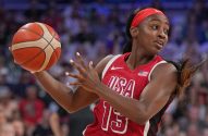 Jogadora de basquete feminina dos EUA, camisa 15, segurando uma bola olímpica, com olhar focado.