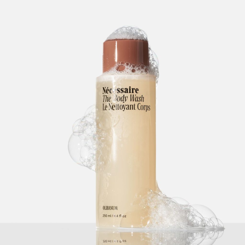 Frasco de Nécessaire The Body Wash com tampa marrom e espuma abundante, em fundo branco.