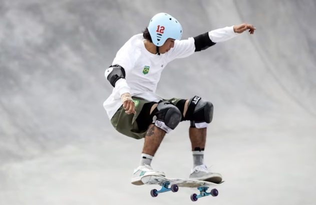 Skatista com capacete azul (nº 12) e logo Brasil, saltando em rampa de skate.