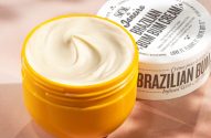 Pote amarelo de creme Sol de Janeiro Brazilian Bum Bum Cream aberto, com creme branco visível e tampa ao lado.