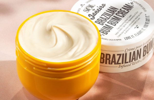 Pote amarelo de creme Sol de Janeiro Brazilian Bum Bum Cream aberto, com creme branco visível e tampa ao lado.