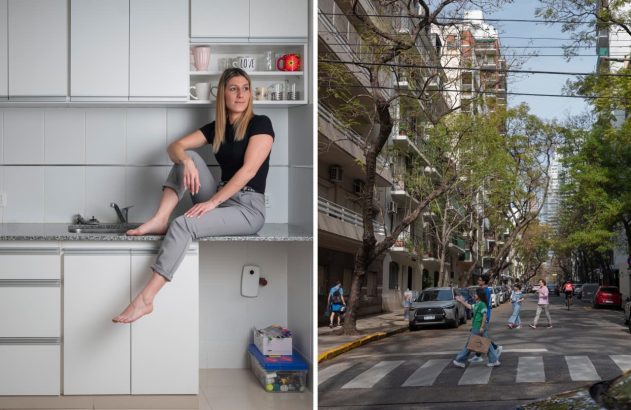 Mulher sorrindo sentada em balcão de cozinha branca; rua urbana com prédios e árvores.