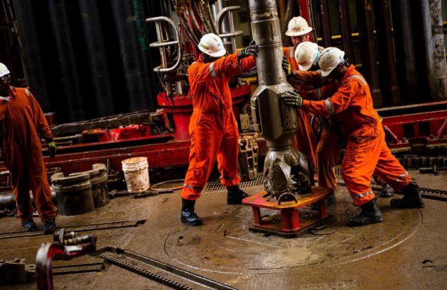 Imagem de técnicos da TotalEnergies trabalhando com maquinário de produção de petróleo