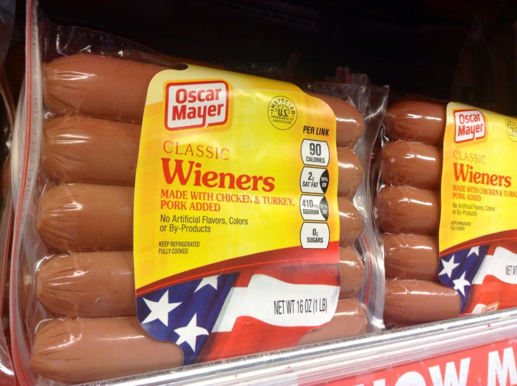 Embalagens de salsichas Oscar Mayer Classic Wieners com rótulo e informações nutricionais em prateleira.