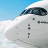 Parte frontal de uma aeronave da Airbus contra um céu azul com algumas nuvens esparsas, mostrando o nariz do avião, a cabine de comando com janelas curvas e o logotipo da Airbus na fuselagem branca.