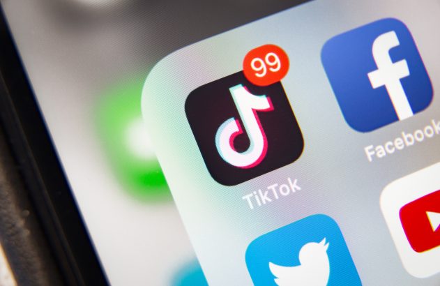 Tela de smartphone exibindo vários ícones de apps, com TikTok mostrando notificação '99'.