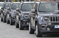 Fileira de SUVs Jeep Renegade cinza-escuro, estacionados em linha ao ar livre.
