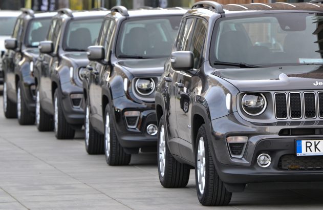 Fileira de SUVs Jeep Renegade cinza-escuro, estacionados em linha ao ar livre.