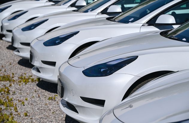 Fileira de carros brancos idênticos estacionados em pátio.