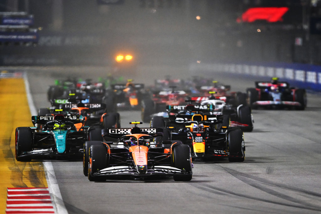 Largada de corrida noturna de Fórmula 1 com múltiplos carros de F1 na pista.