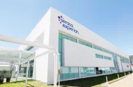 Fachada de prédio com letreiro da empresa Serasa Experian. O prédio tem acabamento em alvenaria branca e vidros azuis espelhados. A imagem tem uma perspectiva forçada, onde se vê a frente a lateral esquerda da edificação.