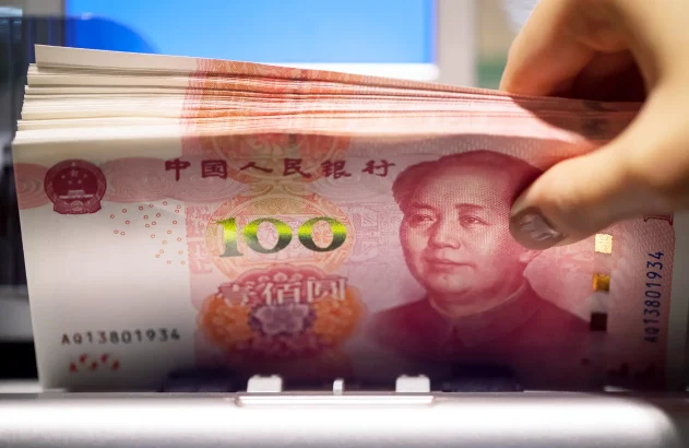 Um trabalhador usa uma máquina para contar notas de 100 yuans chineses em Hong Kong, China.