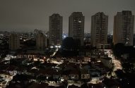 Cidade noturna com prédios acesos e apagão parcial.