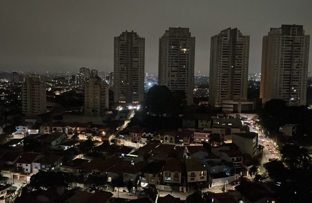 Cidade noturna com prédios acesos e apagão parcial.