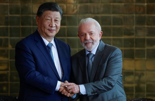 Presidente chinês Xi Jinping e presidente brasileiro Lula da Silva apertam as mãos e sorriem em pose formal.