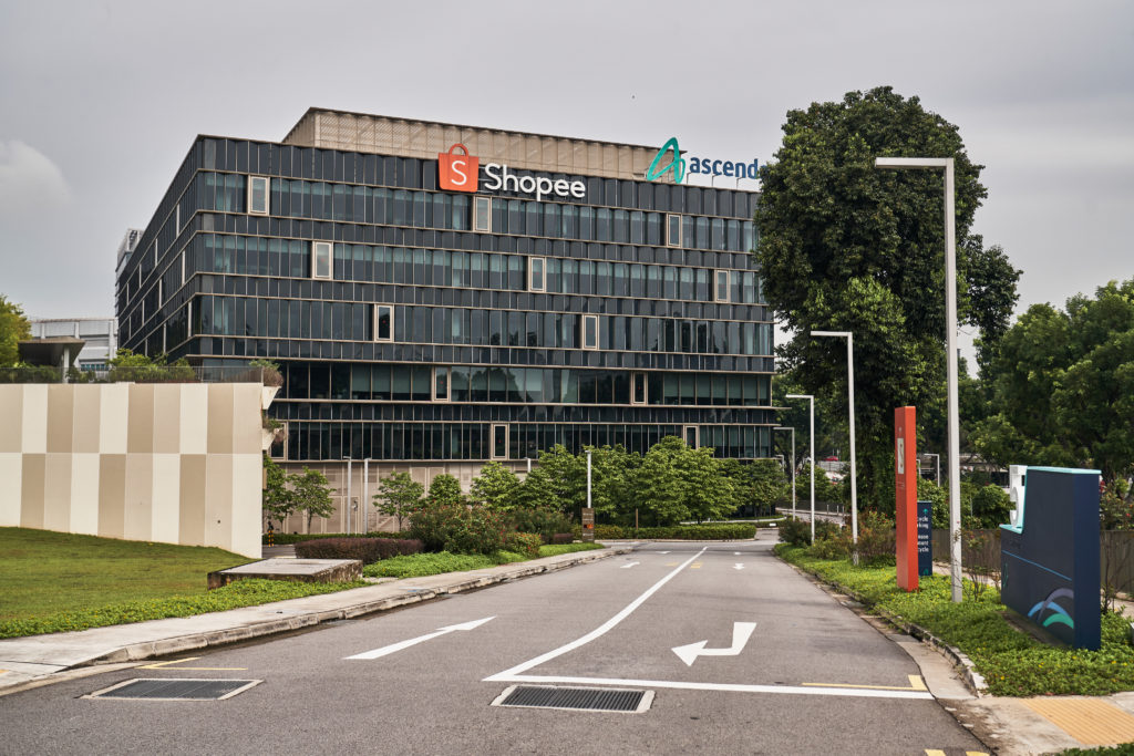 Edifício da Shopee e Ascendas, visto de uma estrada com vegetação.