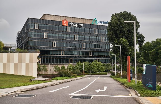 Edifício da Shopee e Ascendas, visto de uma estrada com vegetação.