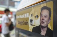 Letreiro mostra Elon Musk, meme Doge e "DogeCoin". Pessoa desfocada ao fundo.