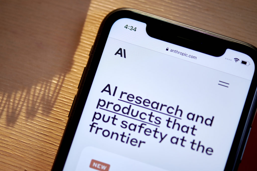 Tela de smartphone exibe site da Anthropic com texto 'AI research and products that put safety at the frontier'.
