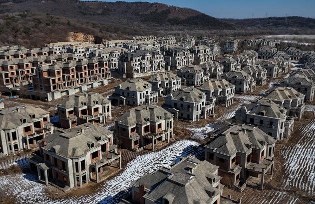 Centenas de casas luxuosas idênticas e inacabadas em terreno árido com neve.