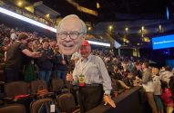 Homem segura recorte de Warren Buffett na reunião de acionistas da Berkshire Hathaway.