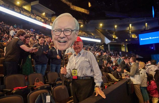 Homem segura recorte de Warren Buffett na reunião de acionistas da Berkshire Hathaway.