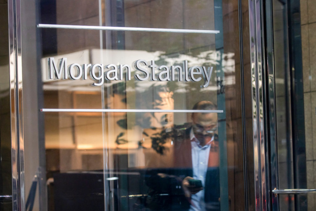 Entrada de vidro com o nome Morgan Stanley refletido e reflexos de pessoas.