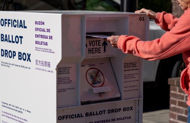 Pessoa depositando voto em caixa eleitoral oficial.
