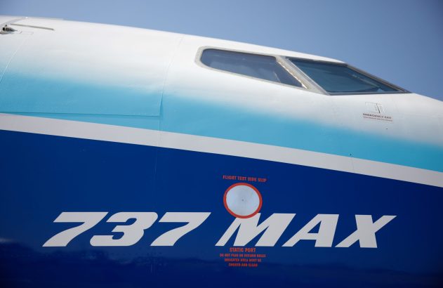 Close-up da fuselagem de um Boeing 737 MAX azul e branco, mostrando o logo e as janelas do cockpit.