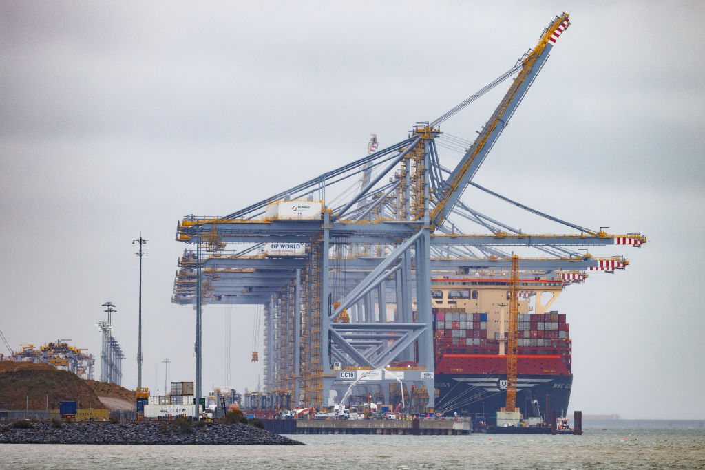 Guindaste em operação sobre navio de contêineres em porto.
