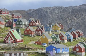 Vilarejo de casas coloridas em encosta de montanha rochosa, sob céu nublado.