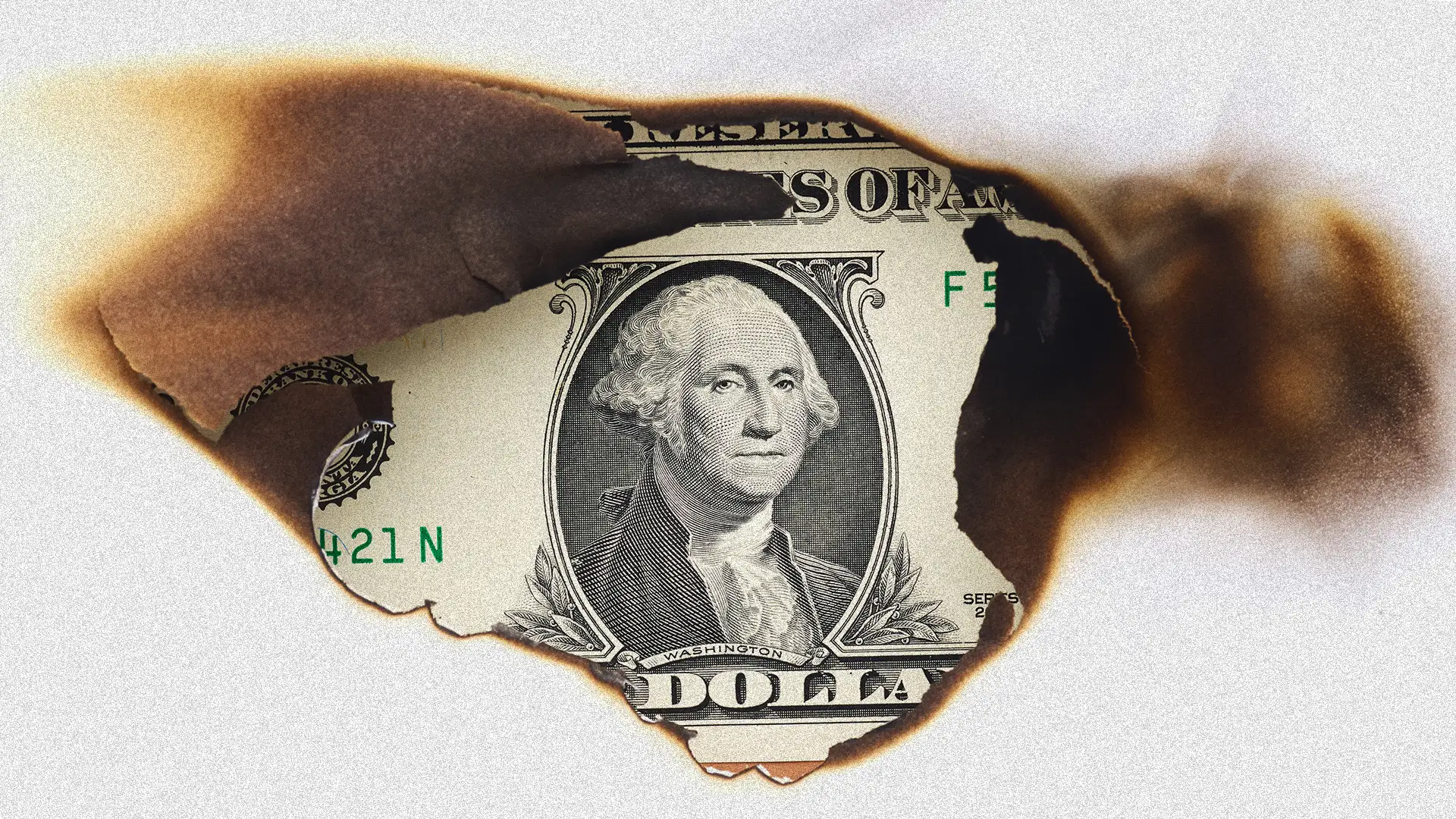 Uma nota de um dólar americano parcialmente queimada e chamuscada, com buracos e bordas carbonizadas, exibindo um retrato visível de George Washington e parte das palavras 