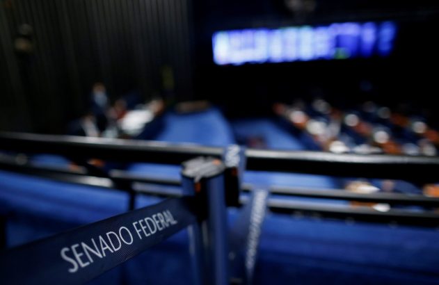 Faixa 'SENADO FEDERAL' em primeiro plano. Plenário com assentos azuis e parlamentares em sessão.